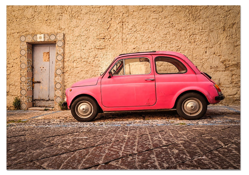 Pink vintage Fiat 500 parked beside a tiled doorway on a Sun worn Italian street – La Cinquecento Rosa by Scotland in Frame