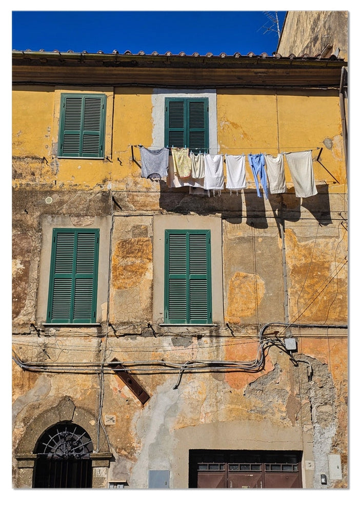 Panni al Vento fine art photograph of washing hanging outside a weathered Italian building with green shutters