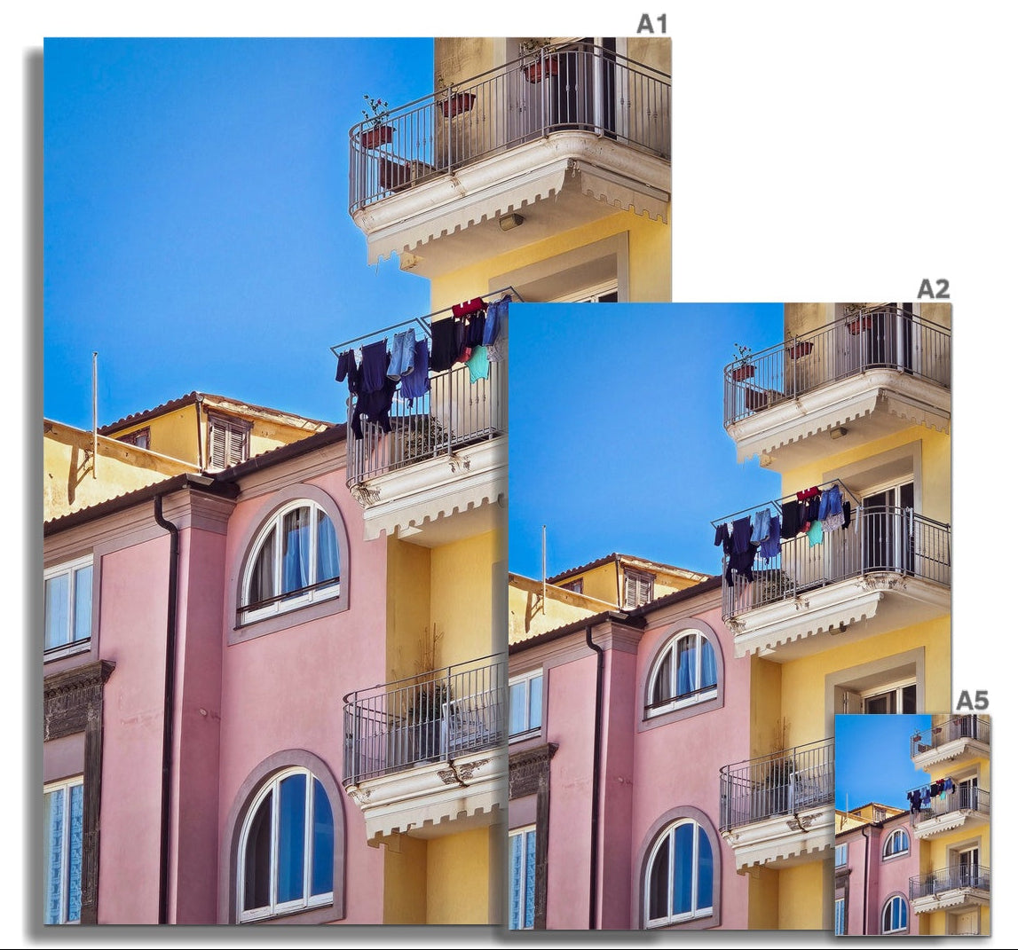 Vita sul Balcone fine art photograph of colourful pink and yellow Italian buildings with balconies and washing beneath a blue sky