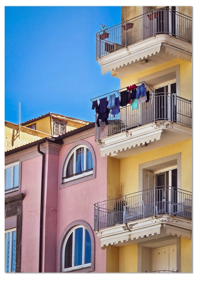 Vita sul Balcone fine art photograph of colourful pink and yellow Italian buildings with balconies and washing beneath a blue sky